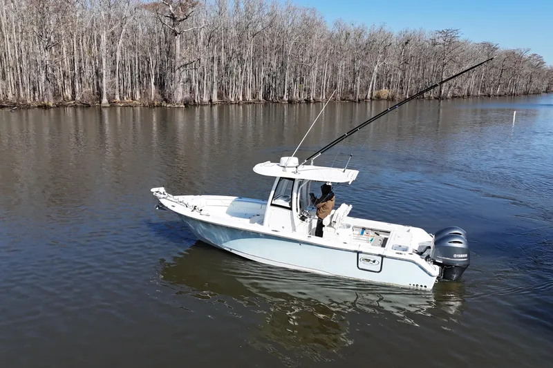 Slide: The Image of 2019 Sea Hunt Gamefish 25 boat on calm river, surrounded by leafless trees. - 21