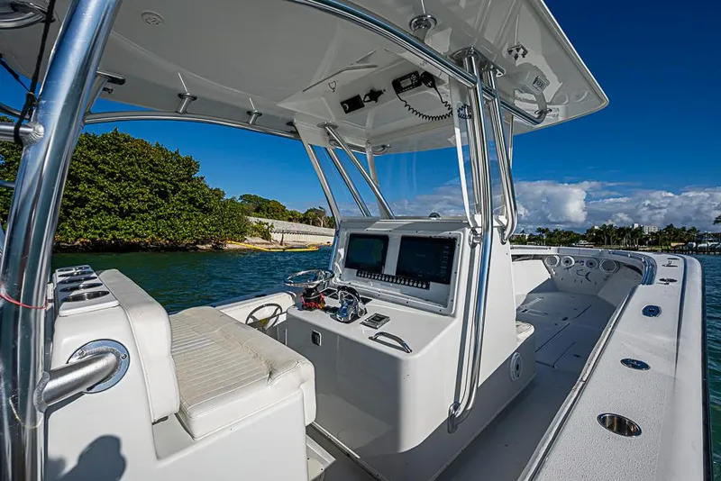 Slide: The Image of 2002 Yellowfin 36 Offshore boat interior with navigation equipment, docked near lush greenery. - 18