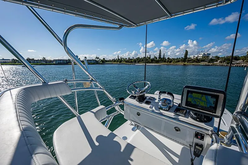 Slide: The Image of 2002 Yellowfin 36 Offshore boat cockpit with navigation equipment, overlooking serene water and distant shoreline. - 25