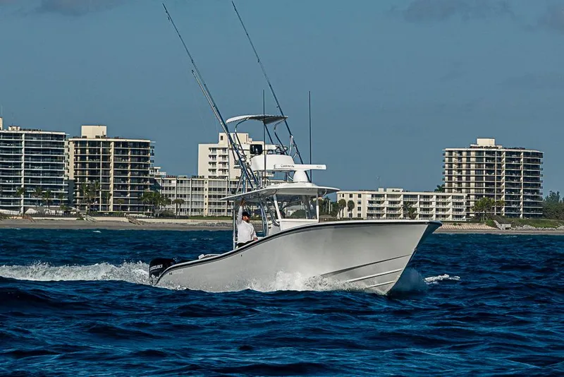 Slide: The Image of 2002 Yellowfin 36 Offshore boat cruising near coastal buildings. - 32