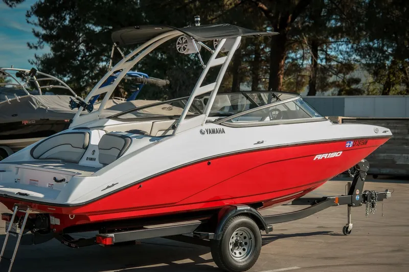 The Image of 2024 Yamaha Boats AR190, red and white, parked on a trailer in a sunny outdoor setting. - 1