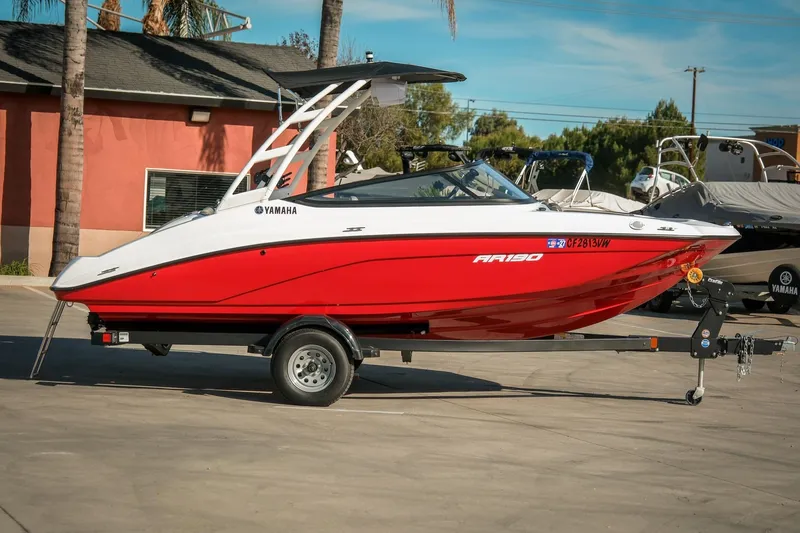 Slide: The Image of 2024 Yamaha AR190 boat in red and white on a trailer, parked outdoors. - 3