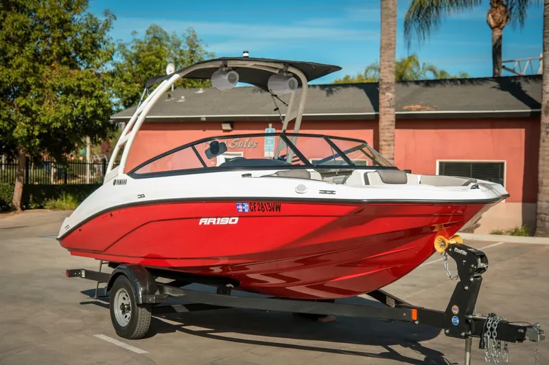 Slide: The Image of 2024 Yamaha AR190 boat in vibrant red on a trailer, parked outdoors. - 9