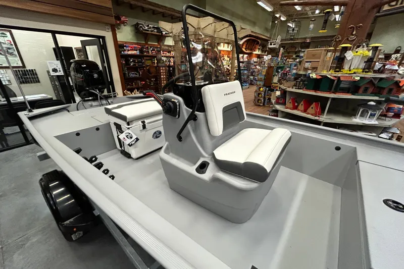 Slide: The Image of 2026 Tracker Bass Tracker Classic CC boat interior with seating and console in showroom. - 2