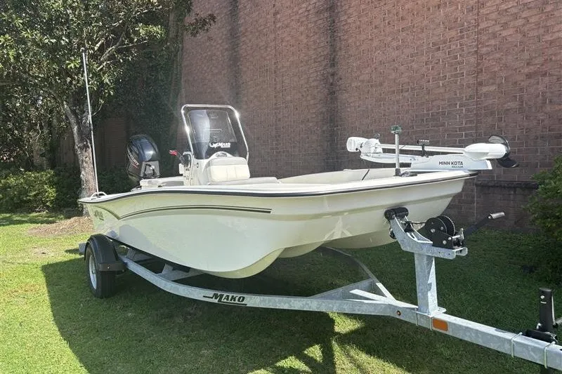 Slide: The Image of 2026 Mako Pro Skiff 15 CC boat on trailer, parked on grass. - 1