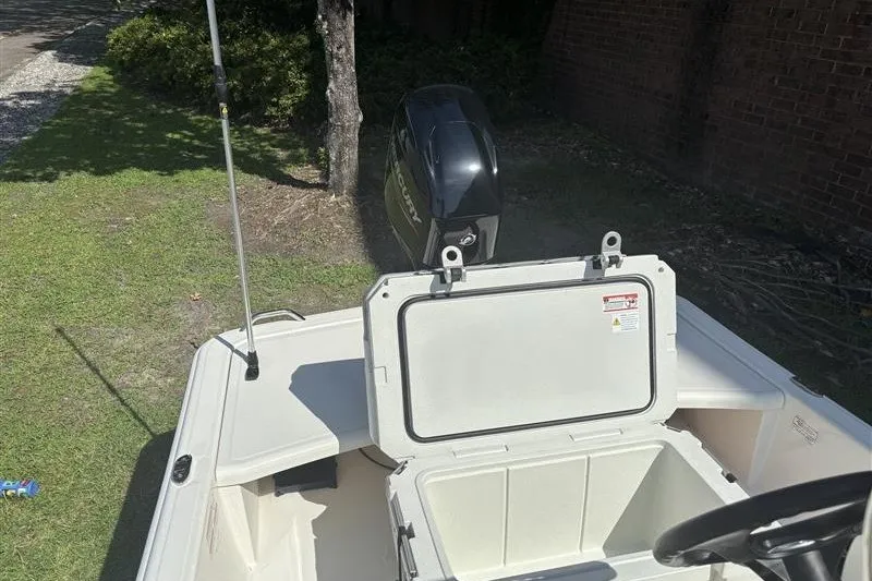Slide: The Image of 2026 Mako Pro Skiff 15 CC boat with open storage compartment and outboard motor. - 10