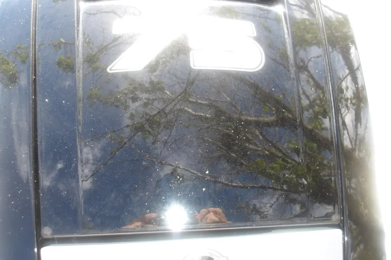 Slide: The Image of Close-up of a boat engine cover with "75" and tree reflections. - 11