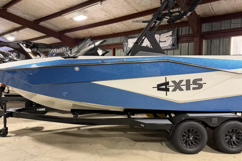 The Image of 2025 Axis T235 boat in showroom, blue and white design, on trailer. - 0