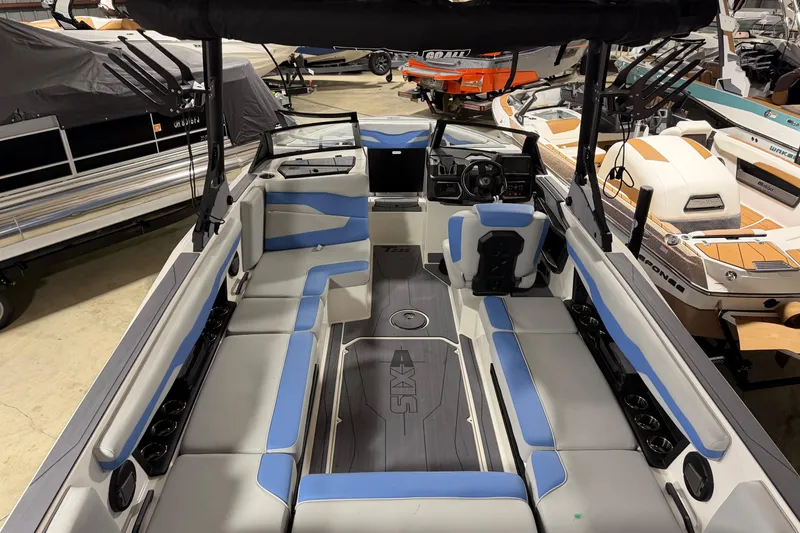 Slide: The Image of 2025 Axis T235 boat interior with blue and gray seating, steering console, and cup holders. - 2