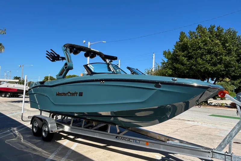 Slide: The Image of 2026 MasterCraft XT24 boat on trailer, sleek design, blue color, sunny day. - 1