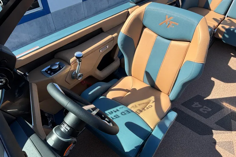 Slide: The Image of 2026 MasterCraft XT24 boat interior with tan and blue seating, steering wheel, and control panel. - 11