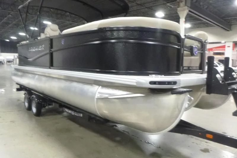 Slide: The Image of 2026 Premier 220 Sunscape RF pontoon boat displayed indoors on a trailer. - 3