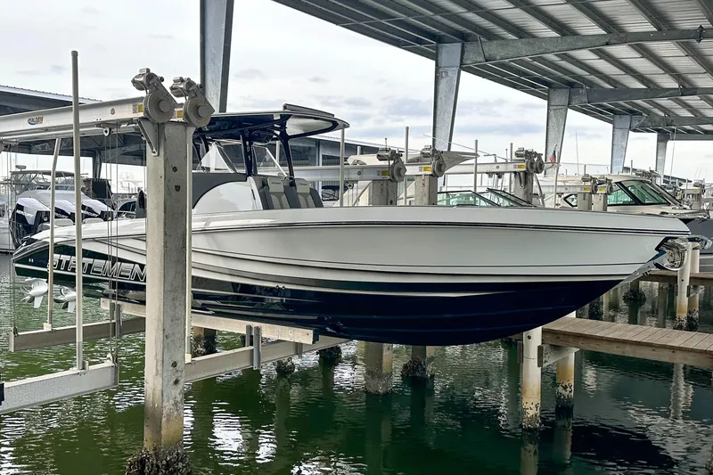 Slide: The Image of 2024 Statement 350 Open boat on lift in marina under metal roof. - 6