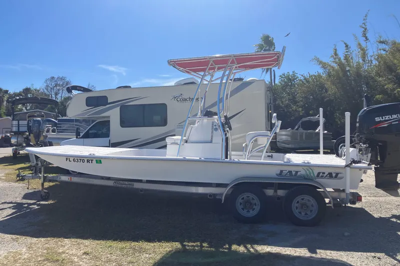The Image of 2016 Fat Cat 21 boat on trailer, parked beside RV under clear blue sky. - 1