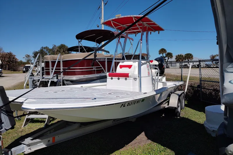 The Image of 2016 Fat Cat 21 boat on trailer, parked outdoors under clear blue sky. - 0