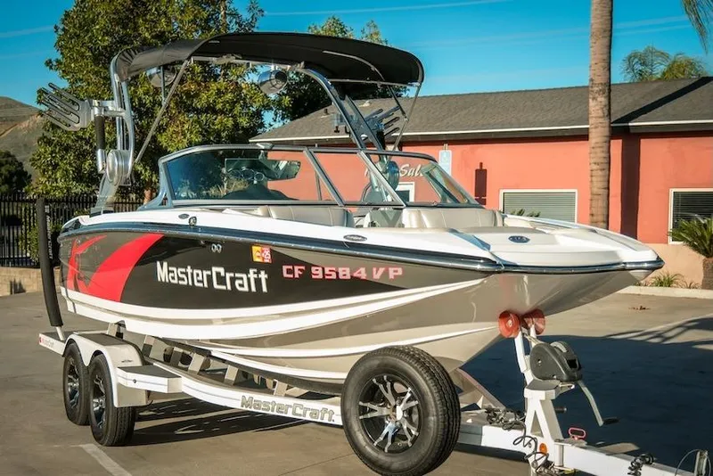 Slide: The Image of 2013 MasterCraft X-2 boat on trailer, parked outdoors, with vibrant graphics and sleek design. - 6