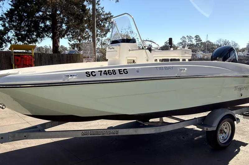 Slide: The Image of 2023 Trophy T-18 boat on trailer, parked outdoors, with visible registration number. - 2
