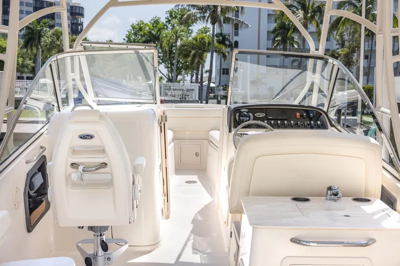 Slide: The Image of 2017 Grady-White Freedom 285 boat interior with helm and seating, docked near palm trees. - 16