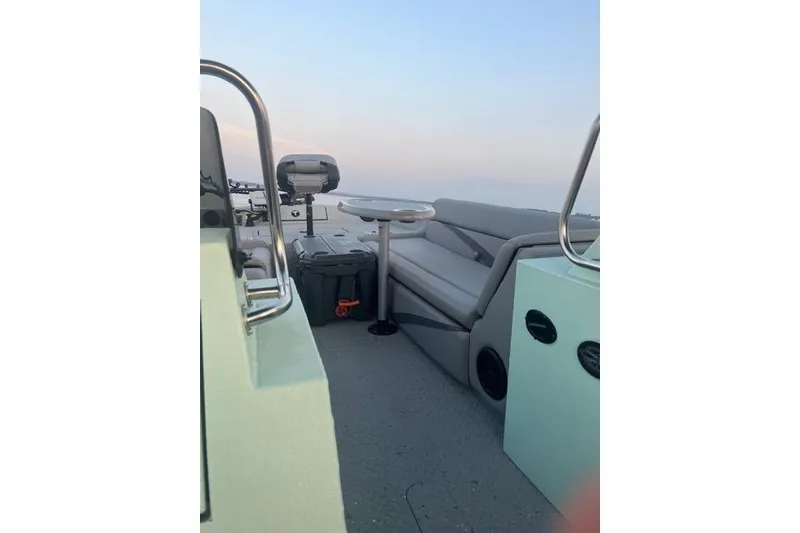 Slide: The Image of 2023 SeaArk Big Easy boat interior with seating and table, under a clear sky. - 10