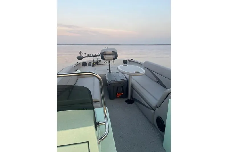 Slide: The Image of 2023 SeaArk Big Easy boat interior with seating and table on calm water. - 11