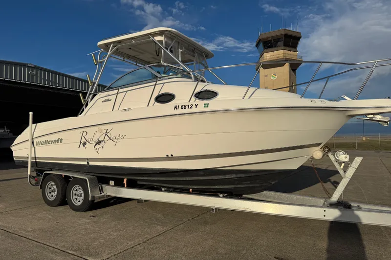 Slide: The Image of 2009 Wellcraft 270 Coastal O/B boat on trailer, parked near an airport control tower. - 0