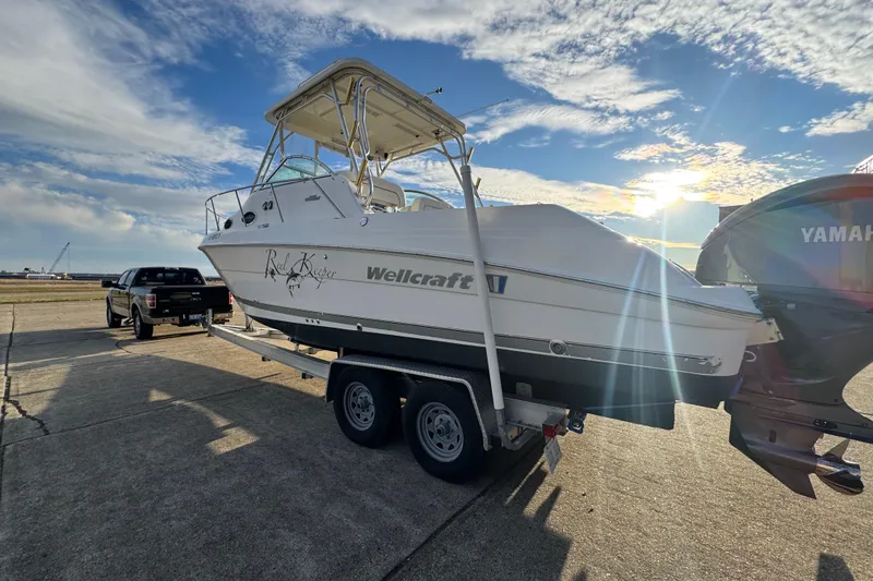 Slide: The Image of 2009 Wellcraft 270 Coastal O/B boat on trailer, sunny day, parked near a truck. - 13