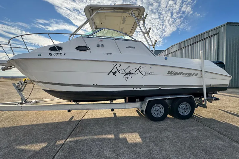 Slide: The Image of 2009 Wellcraft 270 Coastal O/B boat on trailer, parked outdoors under a blue sky. - 16