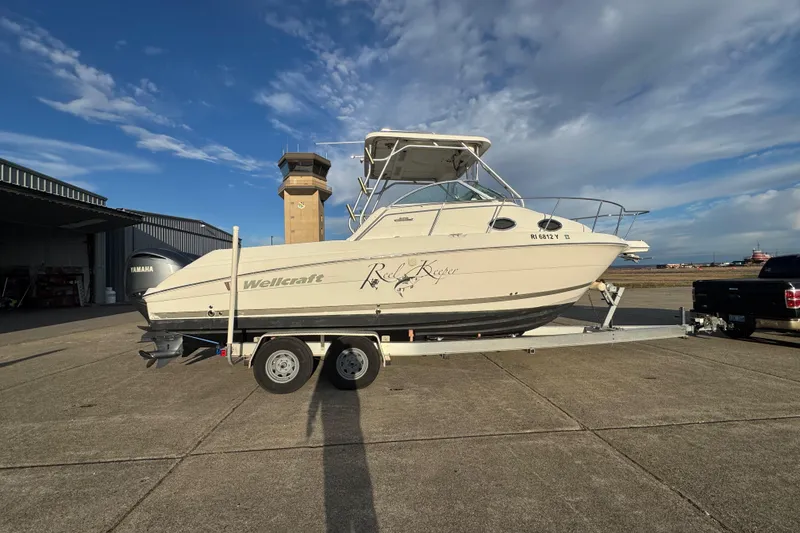 Slide: The Image of 2009 Wellcraft 270 Coastal O/B boat on trailer, parked outdoors under a blue sky. - 7