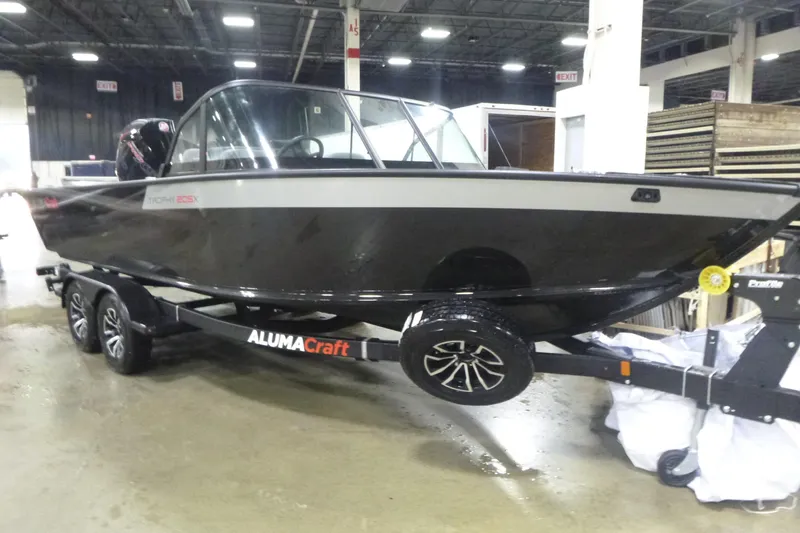 Slide: The Image of 2026 Alumacraft Trophy 205X Sport boat on trailer in indoor setting. - 1
