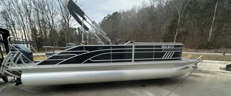 The Image of 2023 Bennington 23 LSB pontoon boat on concrete surface, surrounded by trees. - 0