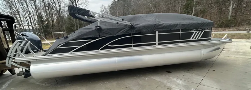Slide: The Image of 2023 Bennington 23 LSB pontoon boat with cover, parked on concrete. - 10
