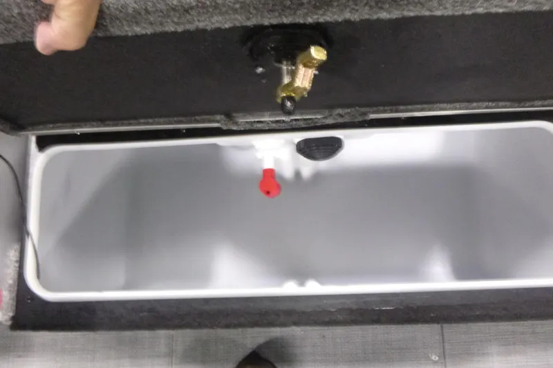 Slide: The Image of Livewell compartment in 2025 Alumacraft Trophy 205X Sport boat, featuring a red valve. - 14