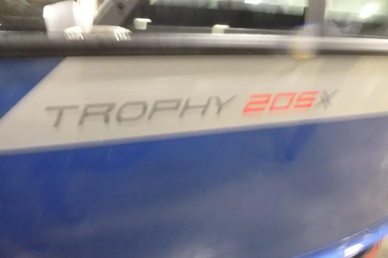 Slide: The Image of 2025 Alumacraft Trophy 205X Sport boat, blue exterior with model name visible. - 17
