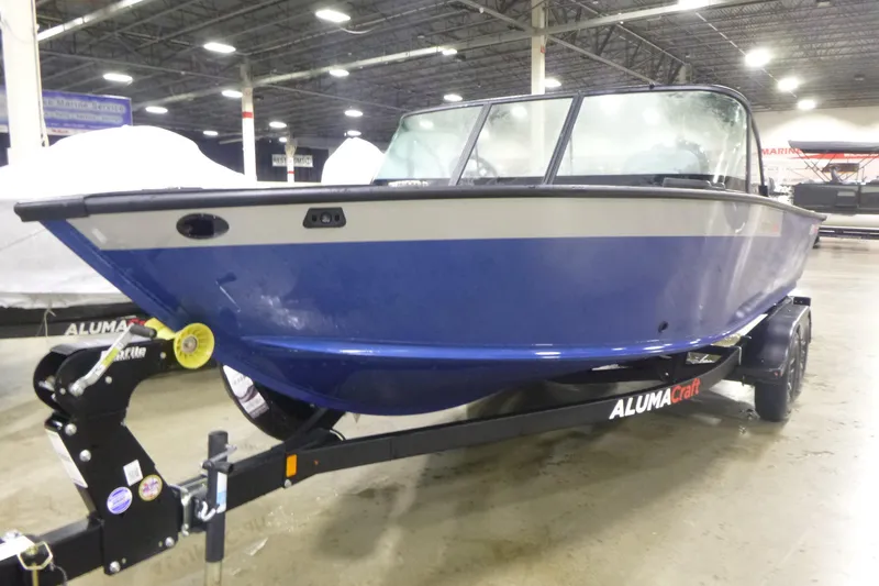 Slide: The Image of 2025 Alumacraft Trophy 205X Sport boat in showroom, blue exterior on trailer. - 2