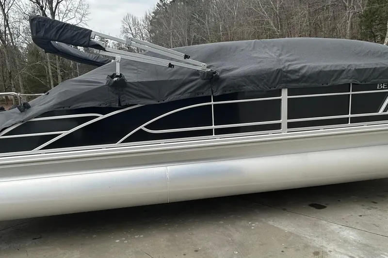 Slide: The Image of 2023 Bennington L 23 Swingback pontoon boat with cover, parked outdoors. - 11