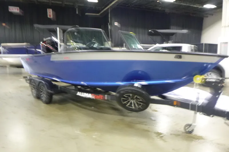 Slide: The Image of 2026 Alumacraft Competitor 205 Sport boat on display indoors, blue exterior. - 3