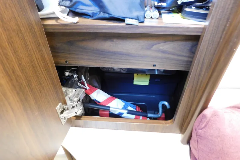 Slide: The Image of Open storage compartment in 2017 Rinker EX 320 boat with various items inside. - 106