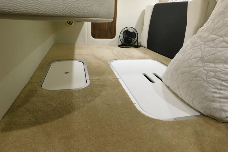 Slide: The Image of 2017 Rinker EX 320 cabin interior with carpet, storage hatches, and a small fan. - 110