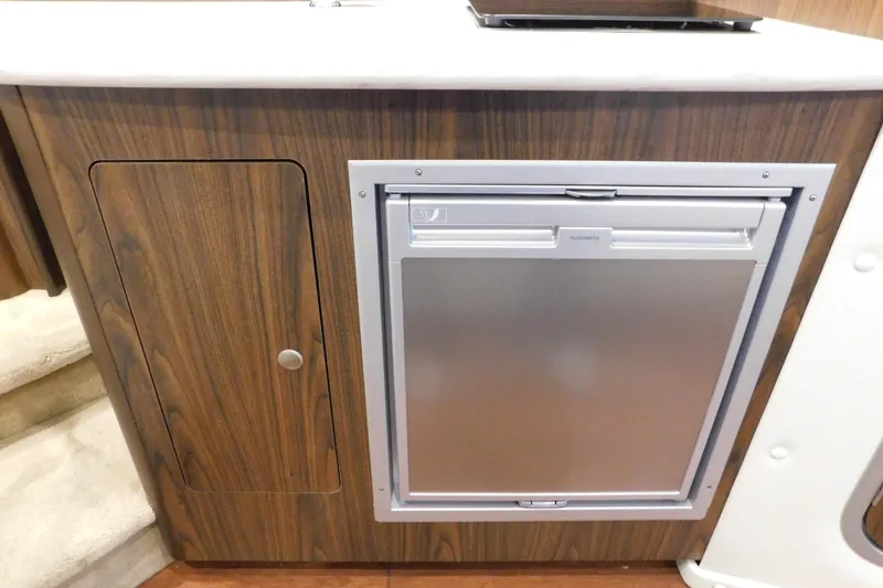 Slide: The Image of 2017 Rinker EX 320 interior with wood paneling and compact refrigerator. - 116
