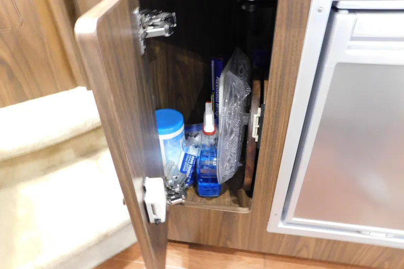 Slide: The Image of Open cabinet in 2017 Rinker EX 320 boat, storing cleaning supplies and kitchen items. - 117
