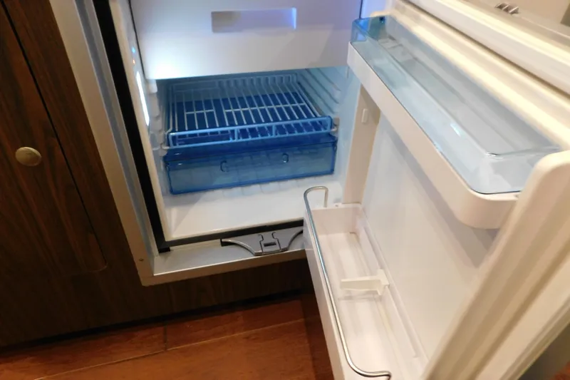 Slide: The Image of Open refrigerator inside a 2017 Rinker EX 320 boat, showing shelves and storage compartments. - 119