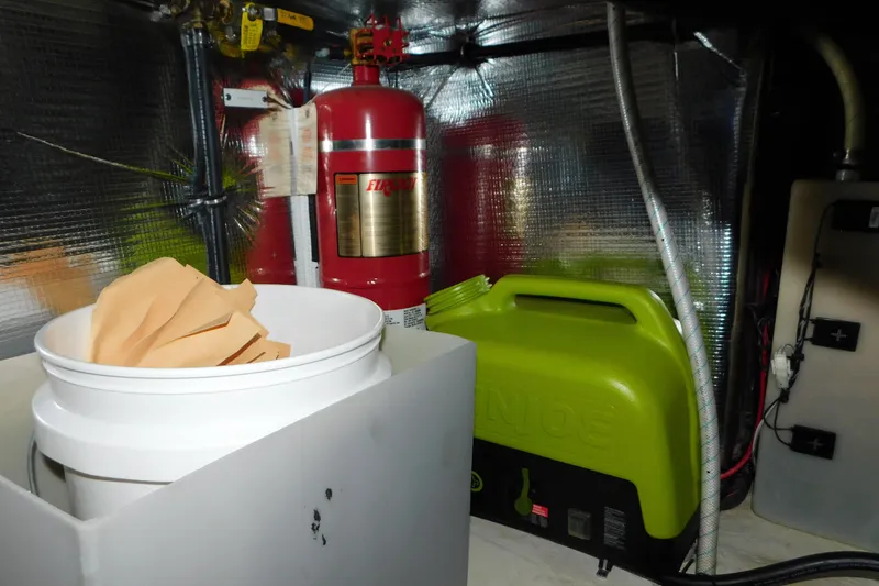 Slide: The Image of 2017 Rinker EX 320 engine room with fire extinguisher and green fuel container. - 129