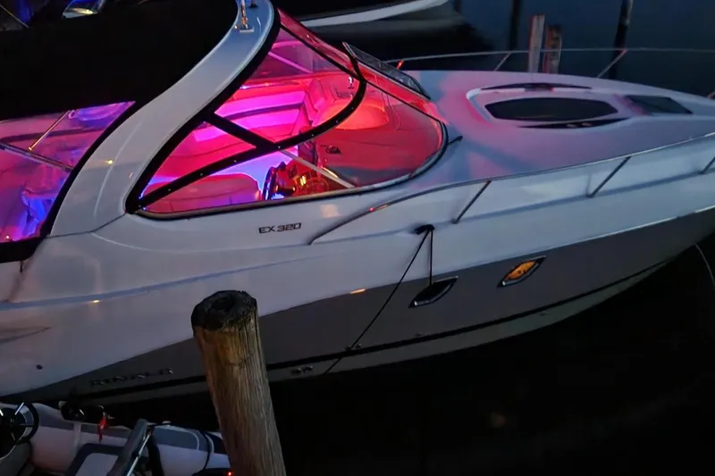 Slide: The Image of 2017 Rinker EX 320 boat with vibrant interior lighting at night. - 2