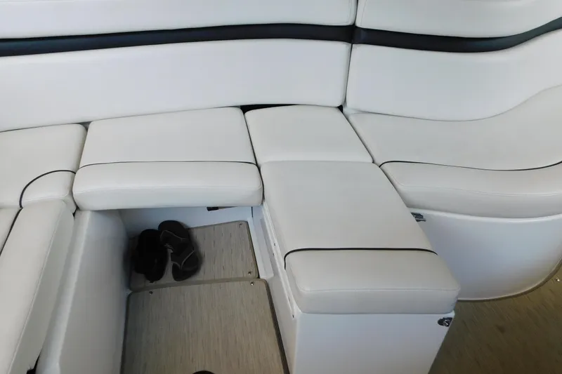 Slide: The Image of 2017 Rinker EX 320 boat interior with white cushioned seating and storage compartment. - 50