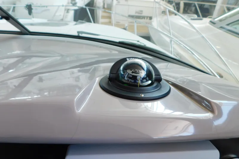 Slide: The Image of Compass on 2017 Rinker EX 320 boat dashboard, with nearby docked vessels. - 63