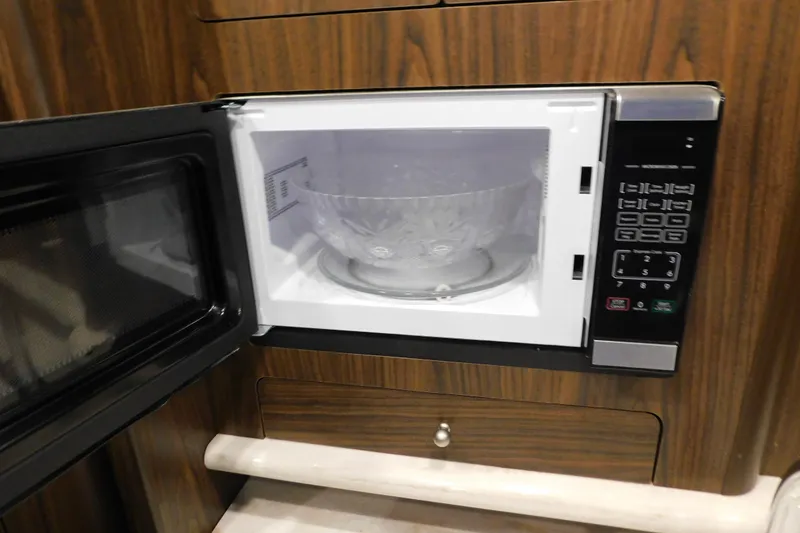 Slide: The Image of Microwave with open door in 2017 Rinker EX 320 boat interior. - 79