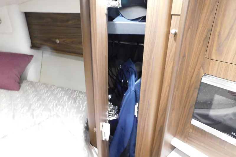 Slide: The Image of 2017 Rinker EX 320 cabin interior with wooden closet and bed. - 82