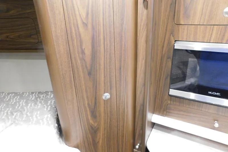 Slide: The Image of Interior of 2017 Rinker EX 320 boat with wood paneling and built-in microwave. - 89