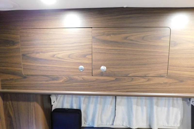 Slide: The Image of Wooden cabinet interior of 2017 Rinker EX 320 boat with overhead lighting. - 98