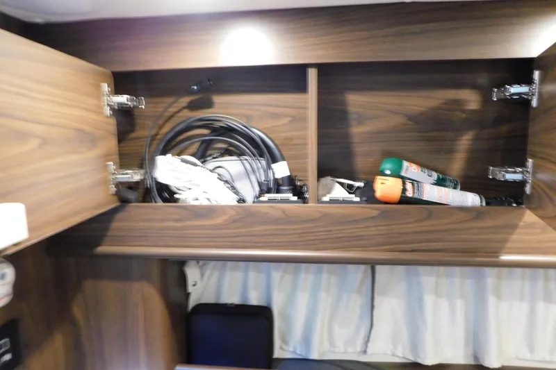 Slide: The Image of 2017 Rinker EX 320 interior cabinet with cables and spray cans. - 99